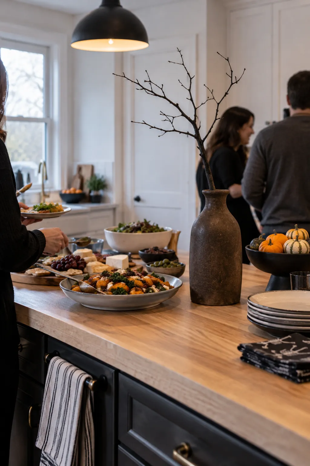 Bare dark branch in a narrow vase behind Halloween party dishes
