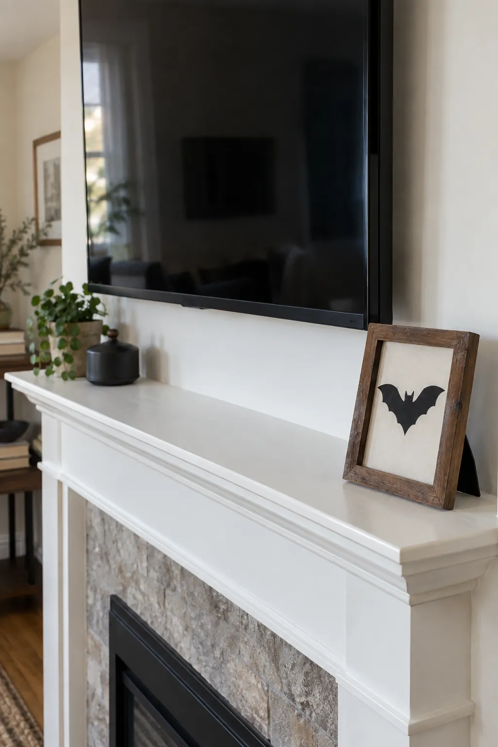 Small framed bat silhouette at the end of a mantel under a television
