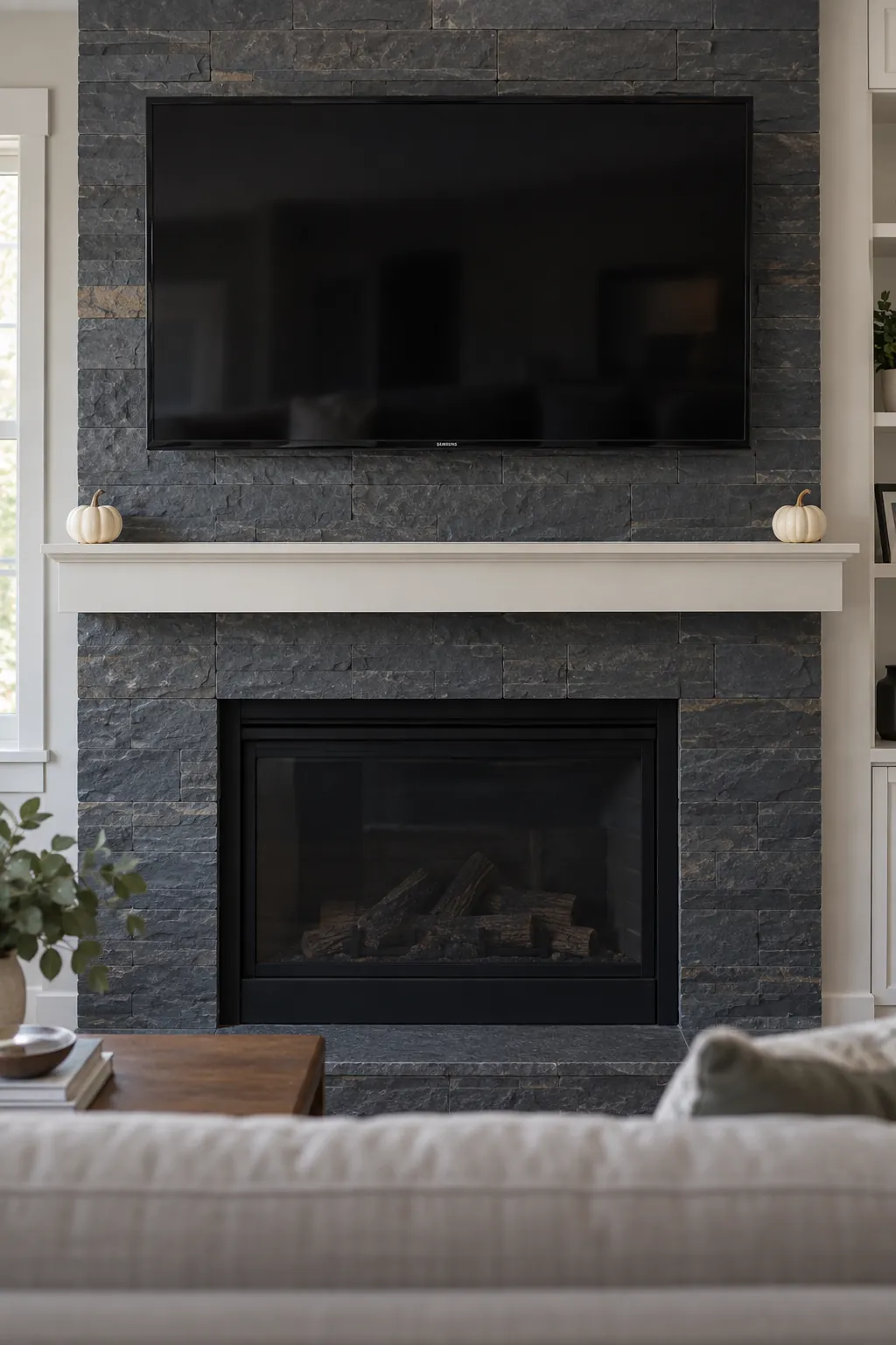 Two small pumpkins at opposite corners of a mantel under a TV