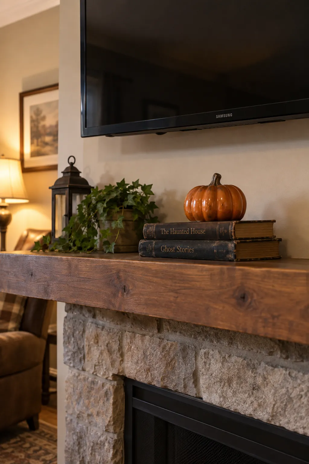 Low stack of books topped by a ceramic pumpkin on a TV mantel