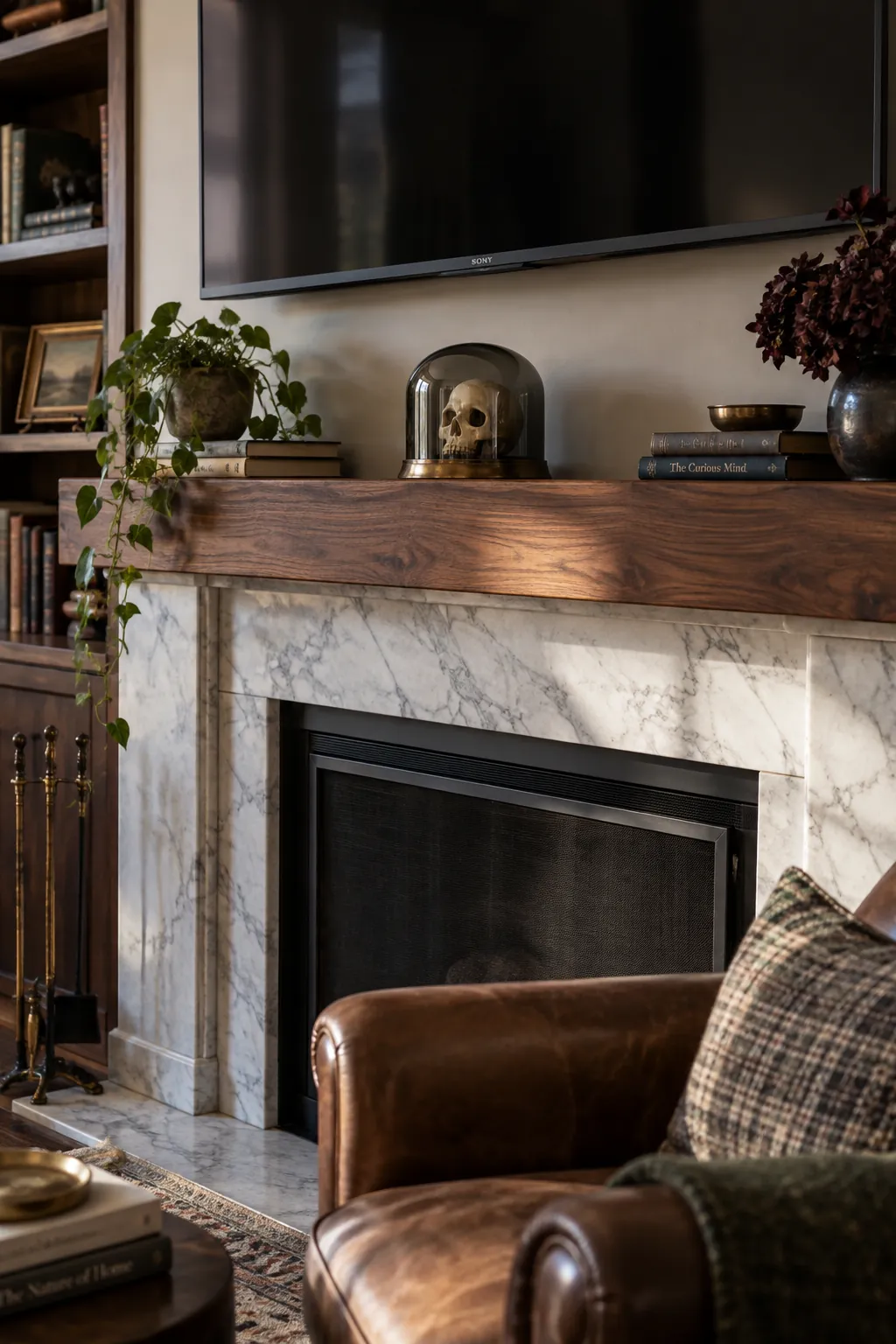 Small skull beneath a low smoky glass cloche on a TV mantel