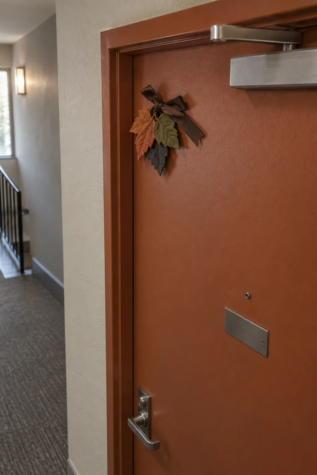 Compact fabric leaf and ribbon decoration at the upper corner of an apartment door
