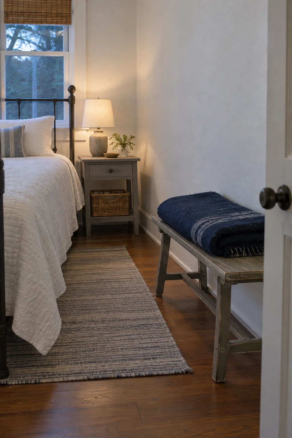 Folded spare blanket on a reachable bench beside a guest bed