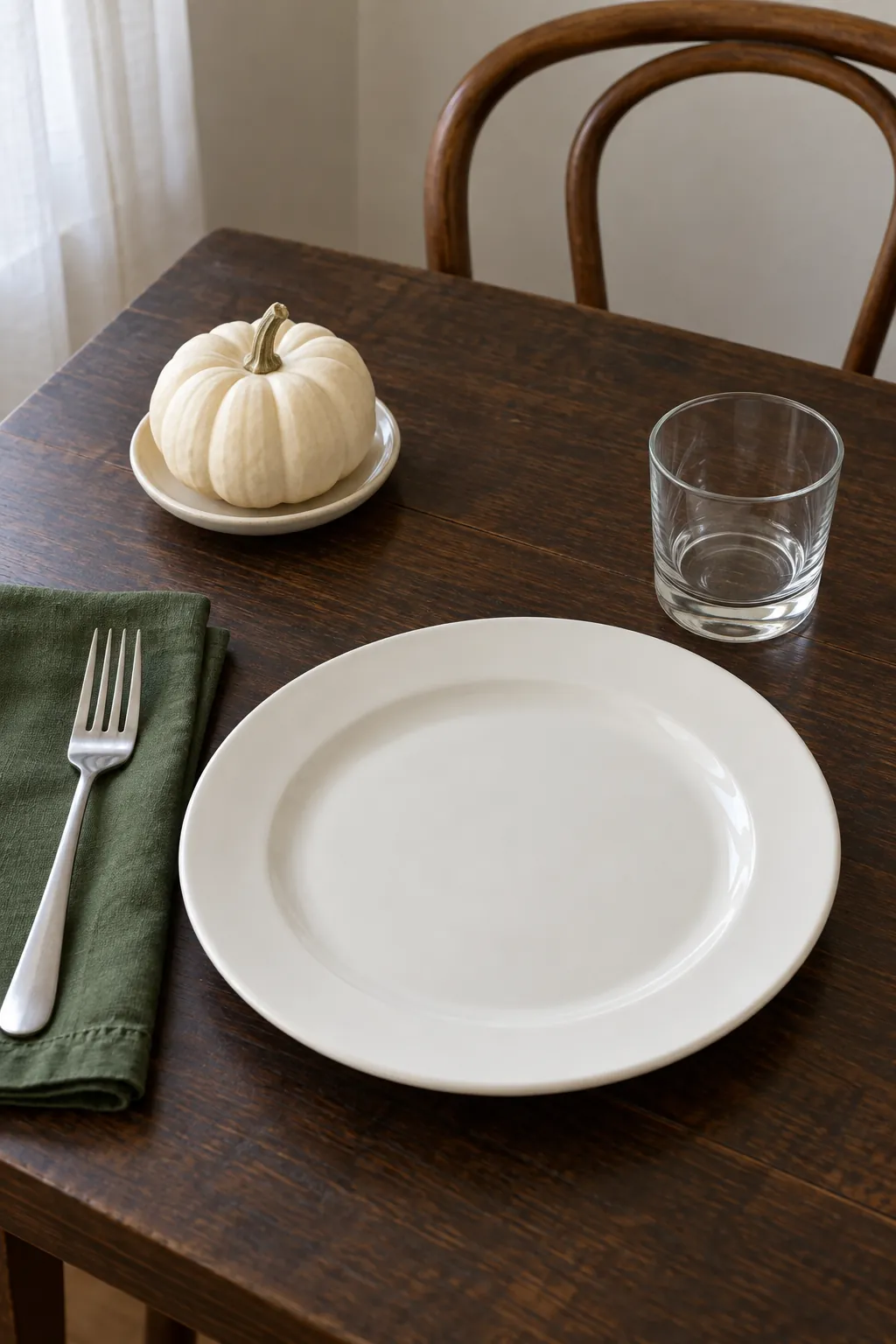A small white pumpkin beyond the plate with everyday white dishes