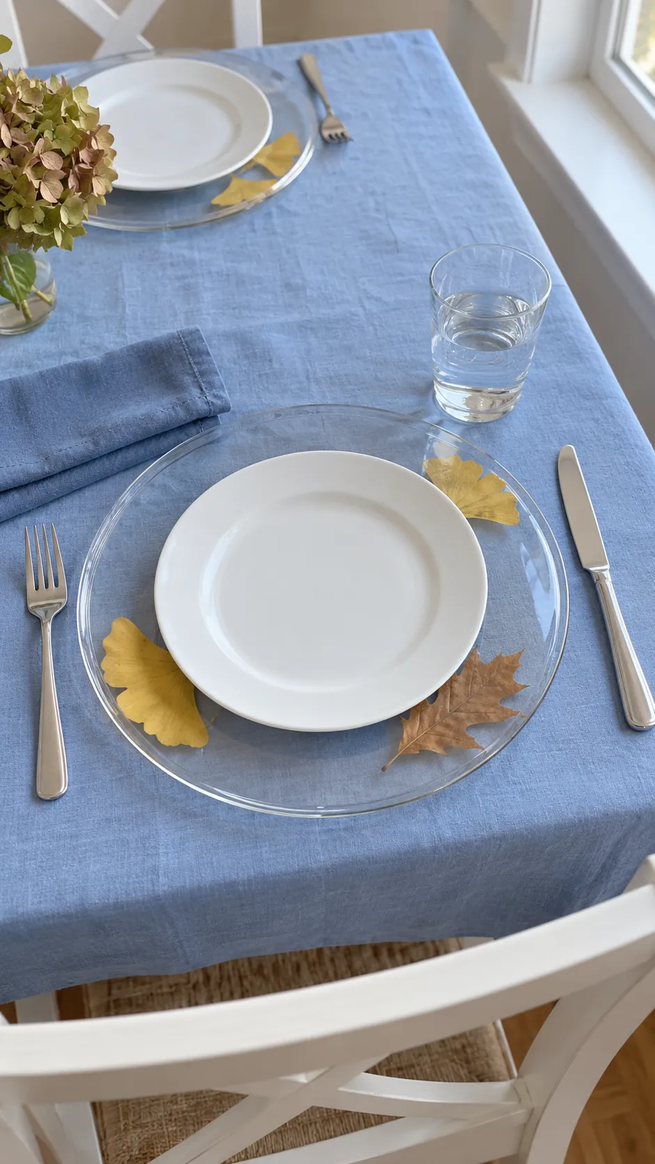 Thanksgiving tablescape featuring pressed leaves beneath clear chargers
