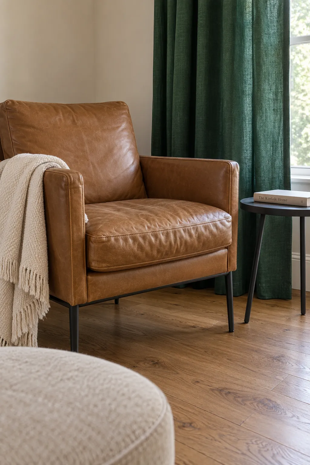 A camel leather chair beside emerald curtains and an existing medium oak floor