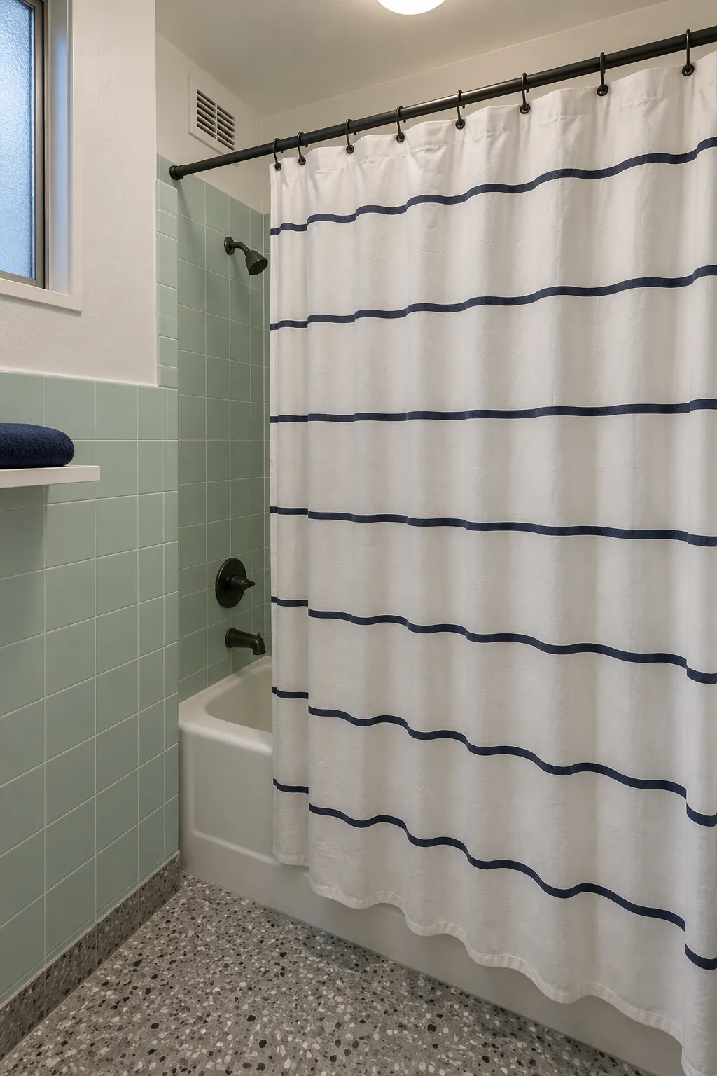 White shower curtain with navy stripes beside pale mint tile