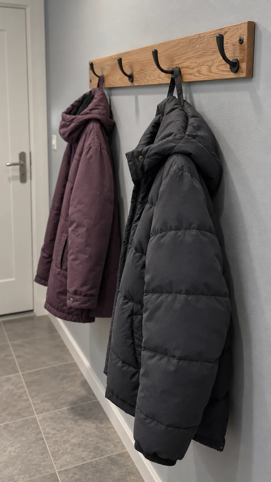 Spaced winter coats on a securely mounted wooden hook rail