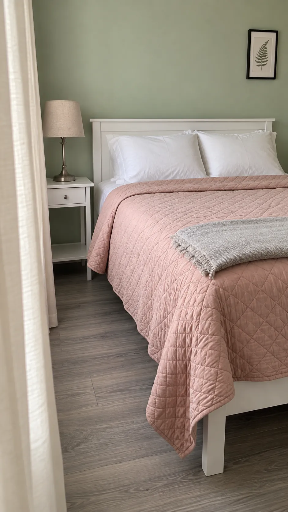 Dusty blush bedding beside light green paint and plain curtains