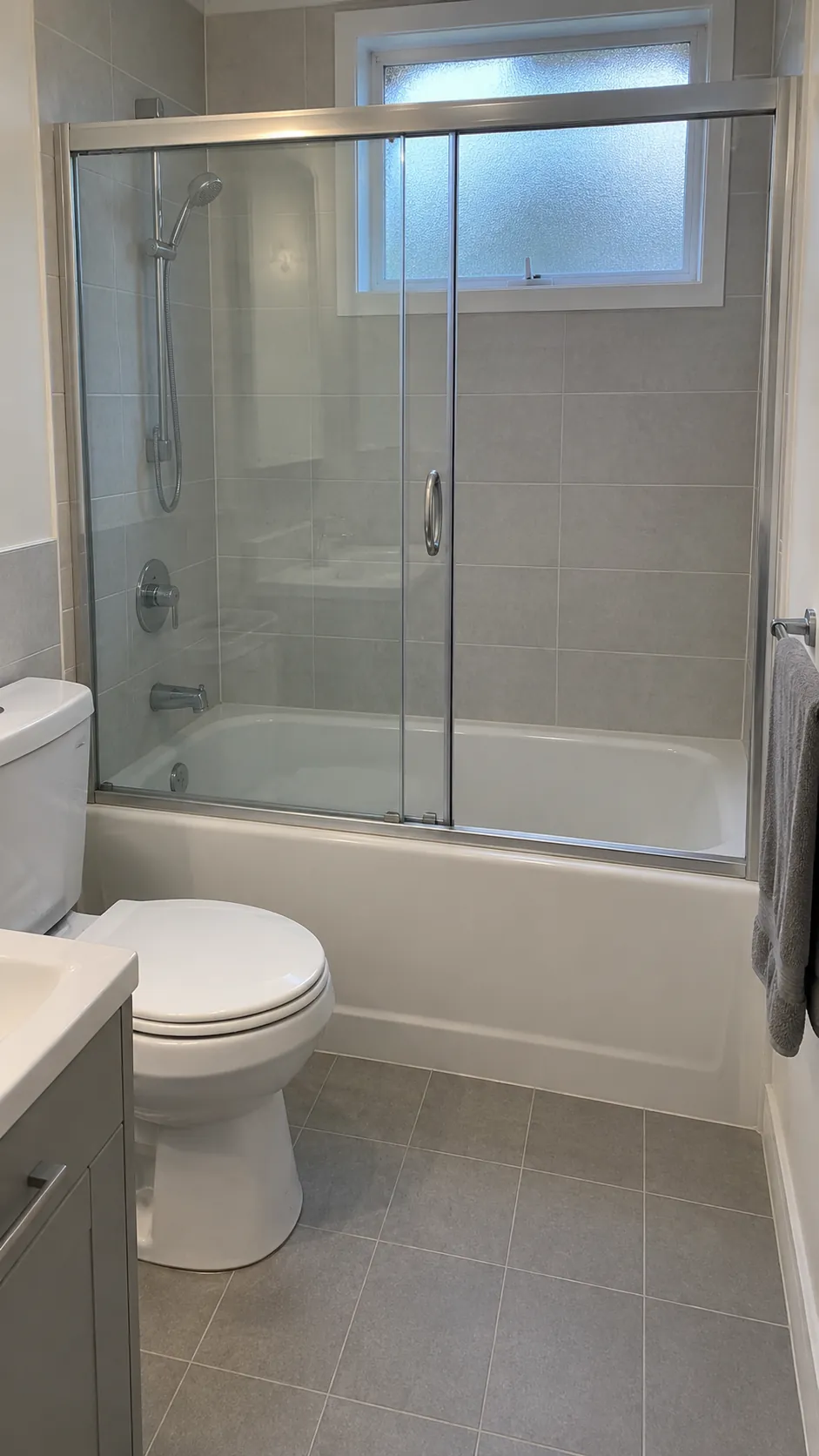 Focus on a sliding bath screen as an alternative to a swinging screen while keeping the established tub, toilet, and vanity arrangement visible.