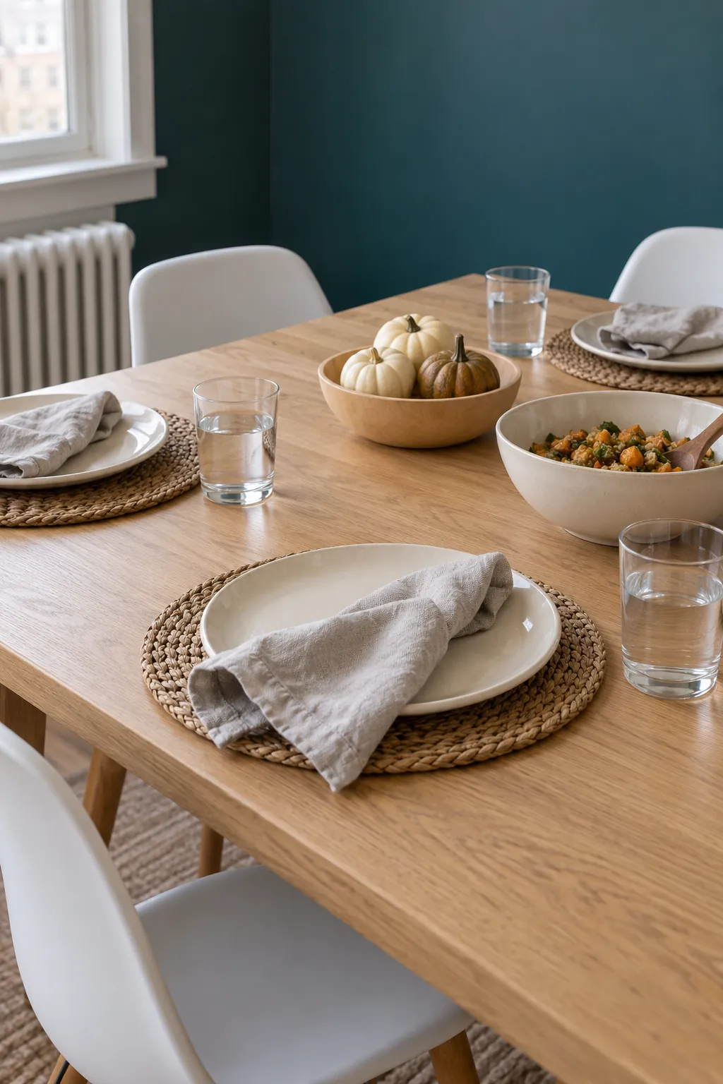 A quiet neutral Thanksgiving table whose linen, woven mats, and pale wood details remain distinct through restrained texture and clear serving space.