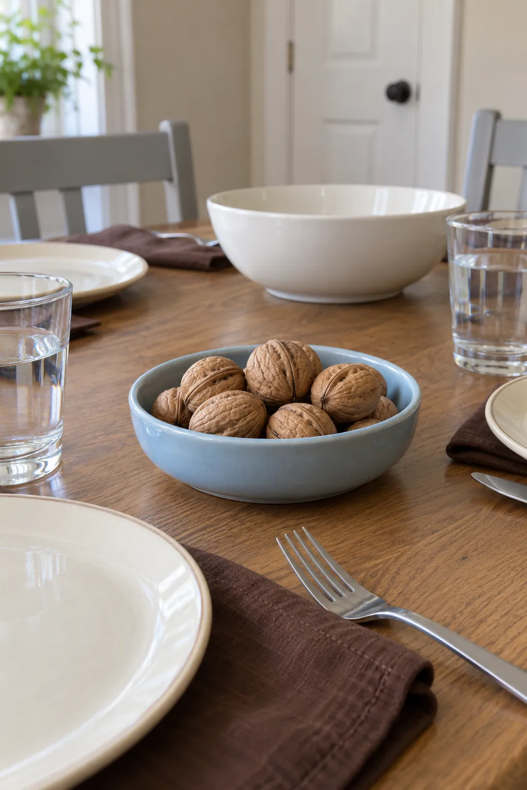 Whole walnuts contained in a shallow ceramic dish as a modest natural Thanksgiving accent.