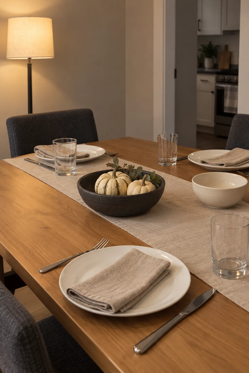 An evening Thanksgiving setting where oat linen keeps one dark pottery accent clearly visible.