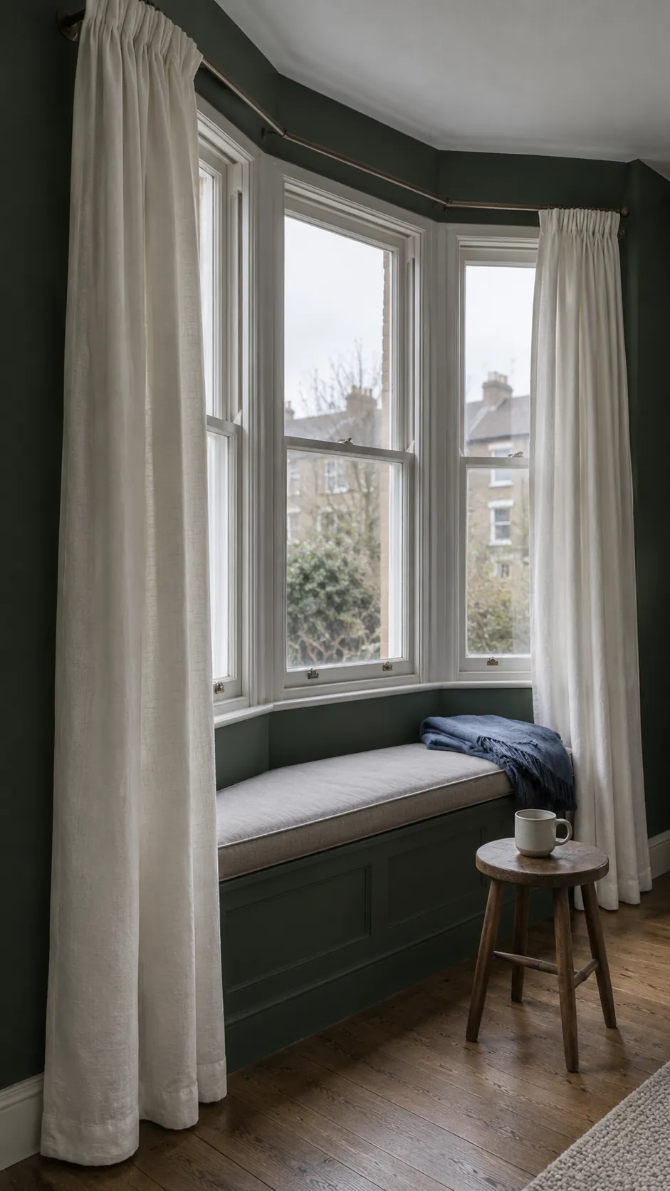 Ivory curtains providing a light edge in a dark green bay window