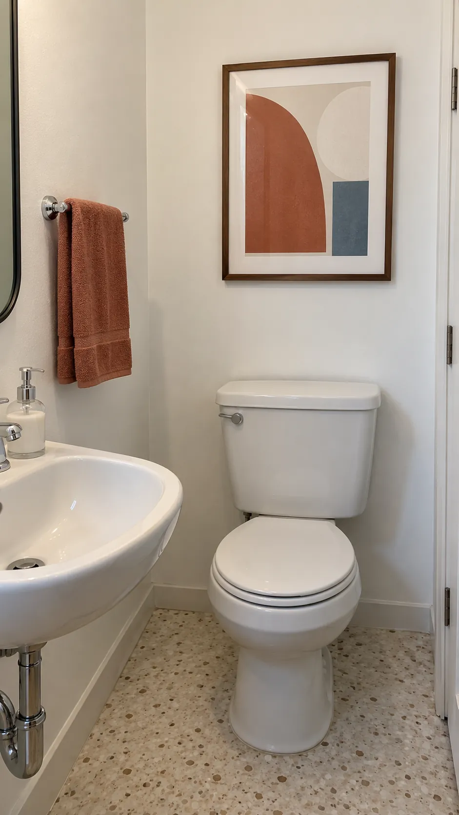 A colorful abstract that echoes the hand towel above a powder room toilet
