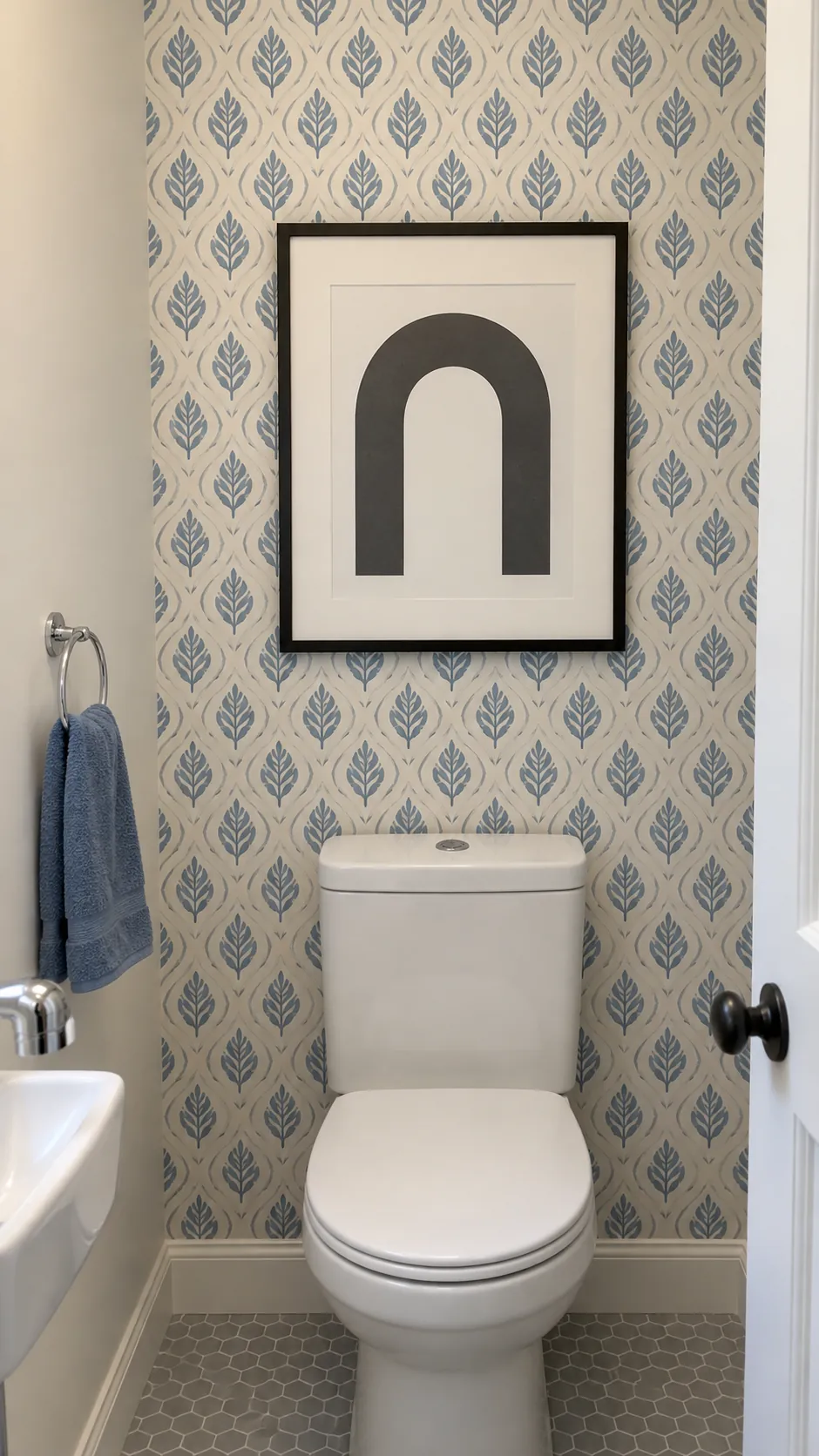 A framed graphic on a patterned wall above a powder room toilet