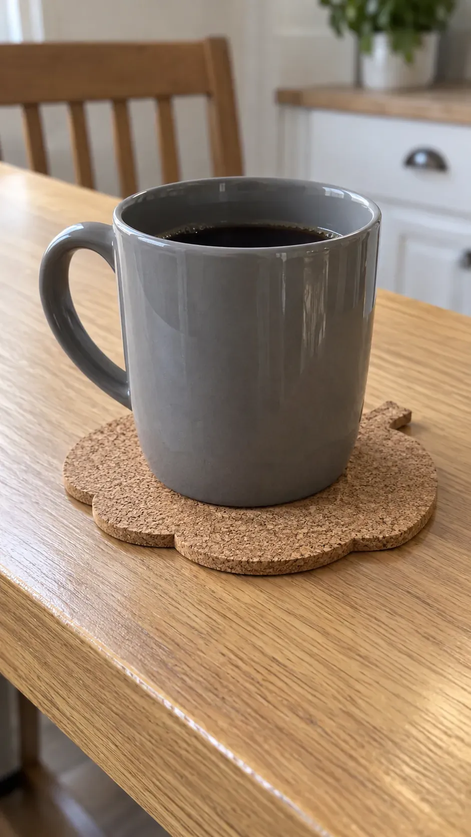 A broad pumpkin shaped plain cork coaster supporting a mug on a breakfast ledge