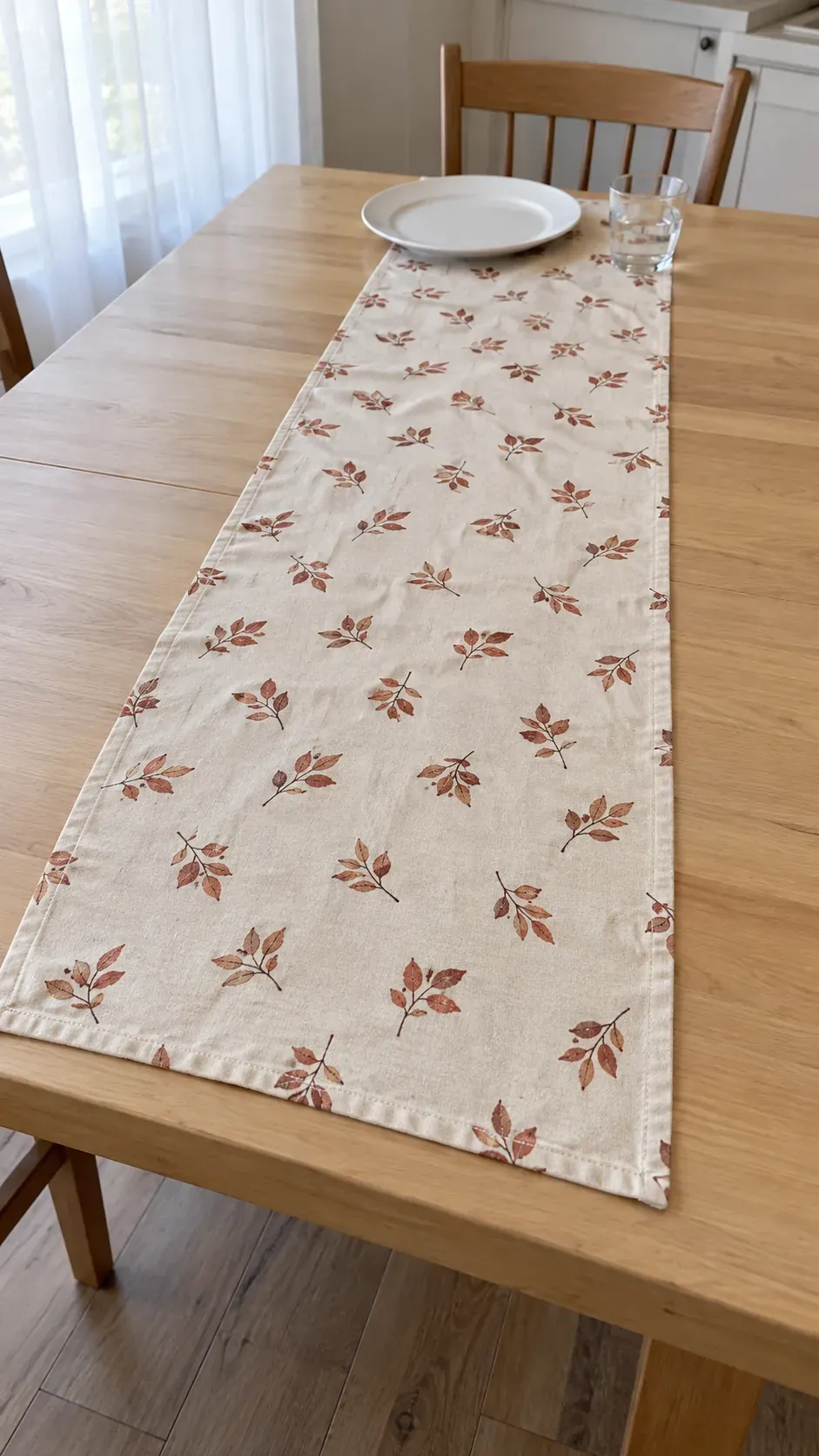 A restrained rust leaf print fabric runner with clean hems on an everyday kitchen table