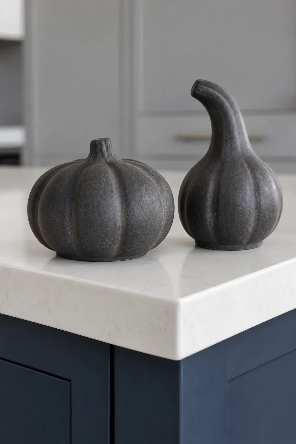 Two matte charcoal ceramic gourds with different shapes grouped on an island corner