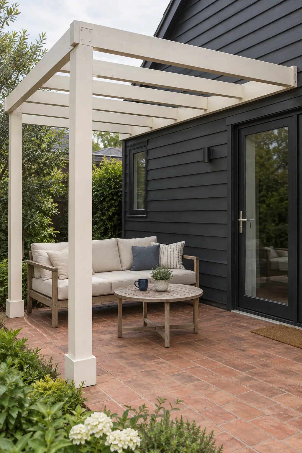 A light painted frame against dark cladding under a pergola beside the house