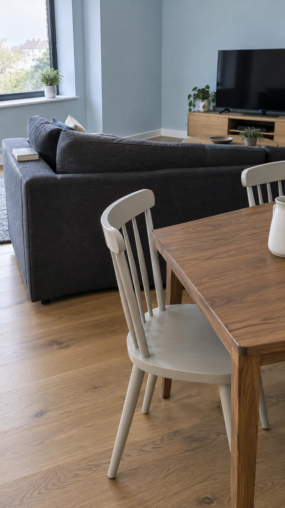 Dining table behind a low sofa with space for chair movement