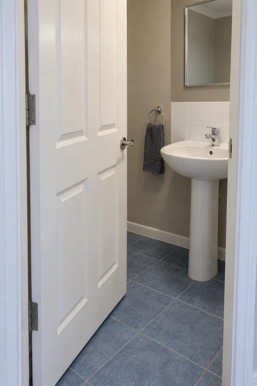 Bathroom door open beside a compact basin with clear separation