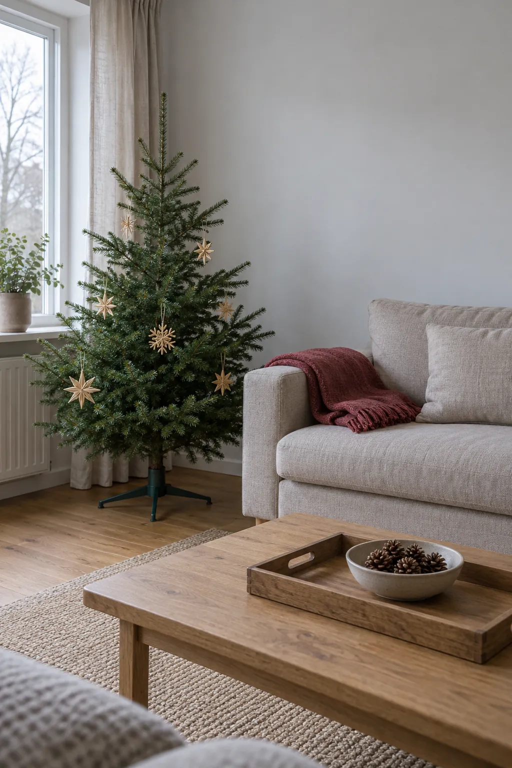 A natural Christmas living room with small fir tree, wool throw and useful wooden tray