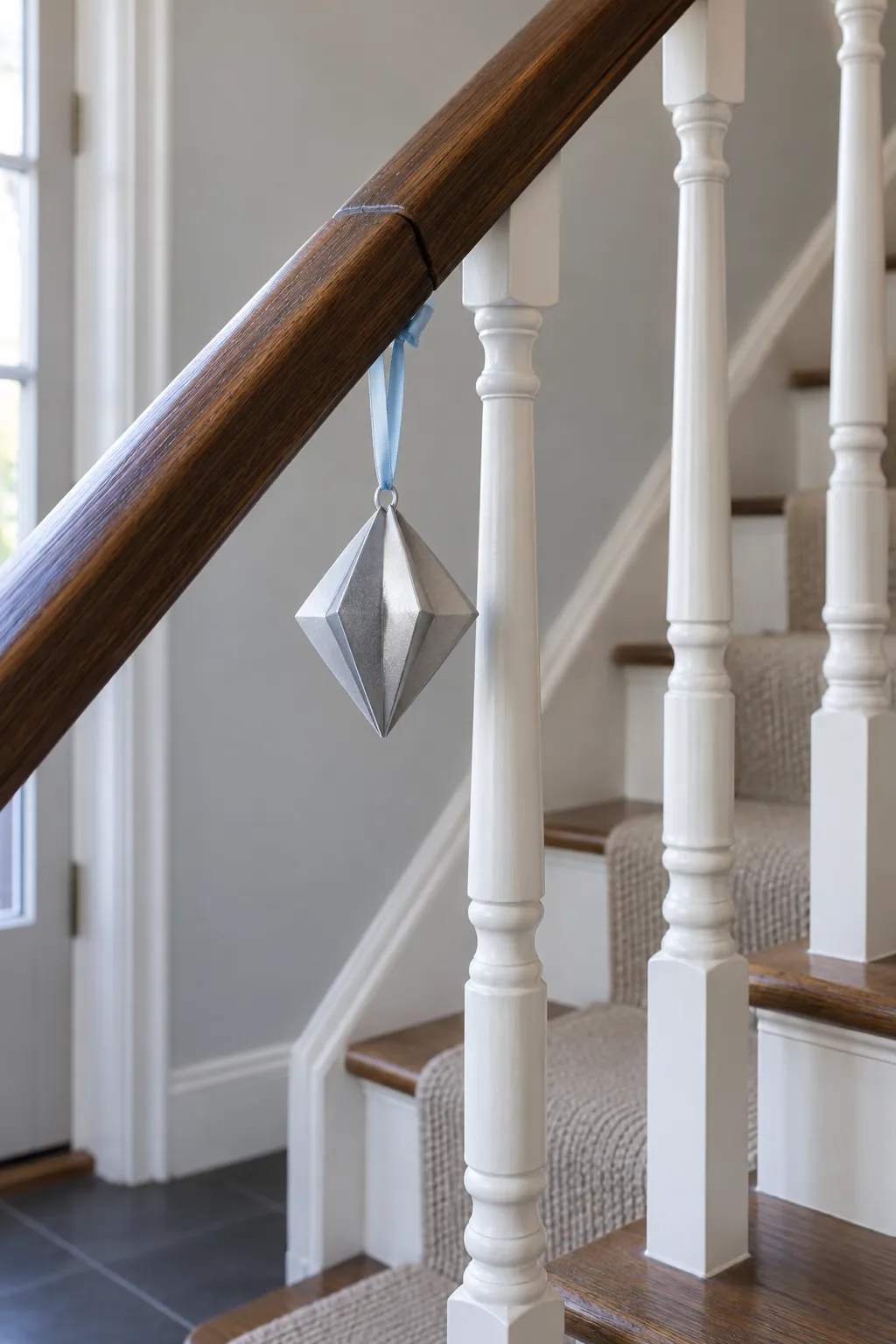 Suspend a light ornament from a stair spindle in a Christmas entryway without a tree