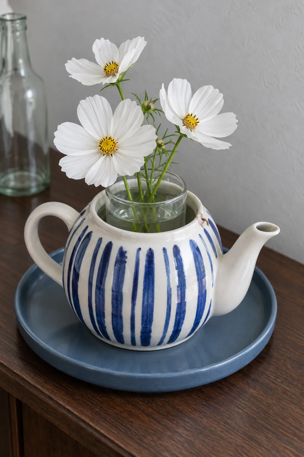 Separate glass vase inside a decorative teapot holding fresh flowers