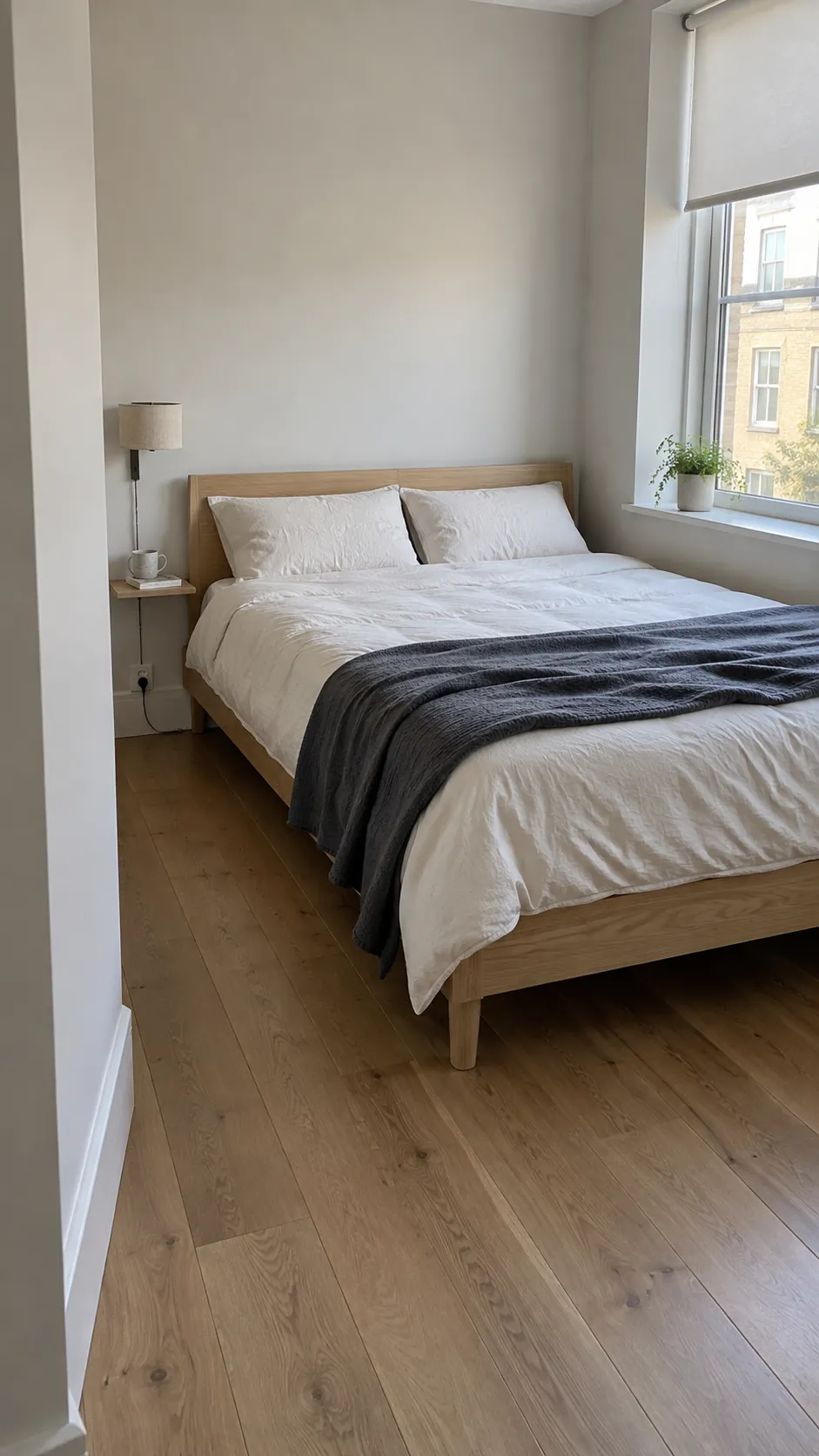 Slim timber bed placed along the long arm of a compact L shaped bedroom