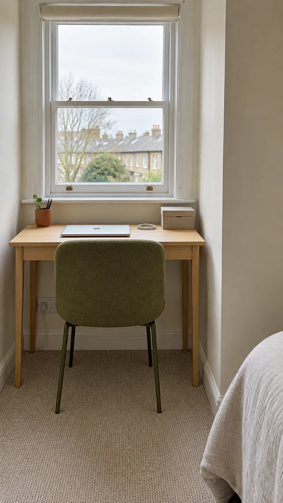 Small desk and tucked chair use the window recess of an L shaped bedroom