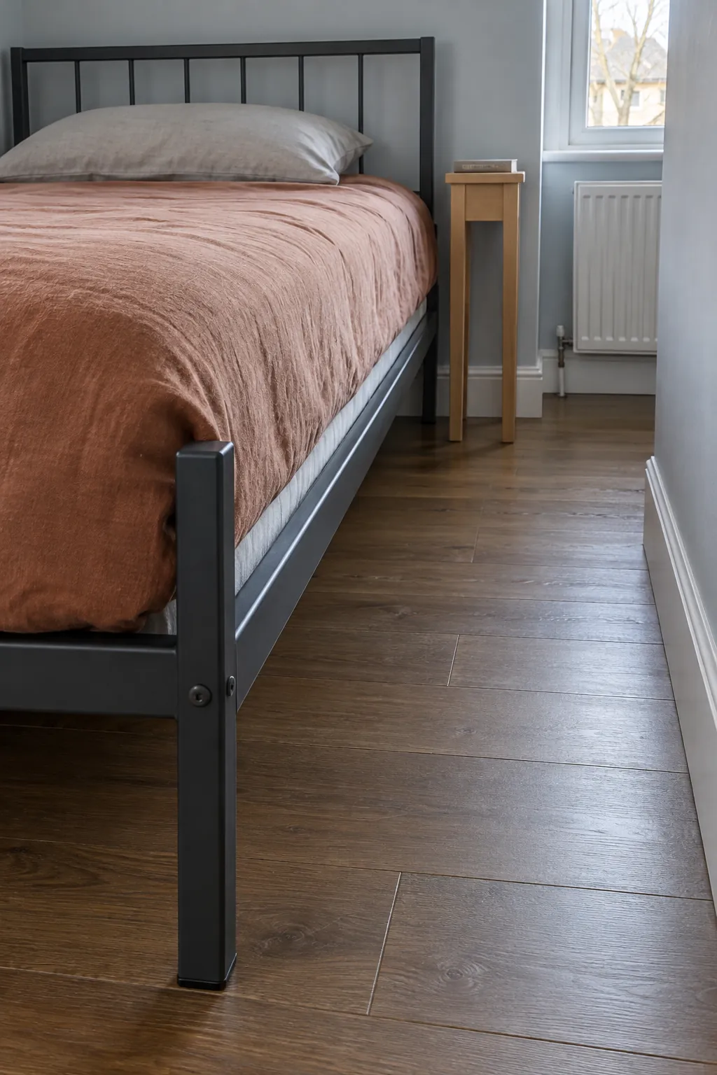 Slim metal bed frame with usable access beside it in a narrow room