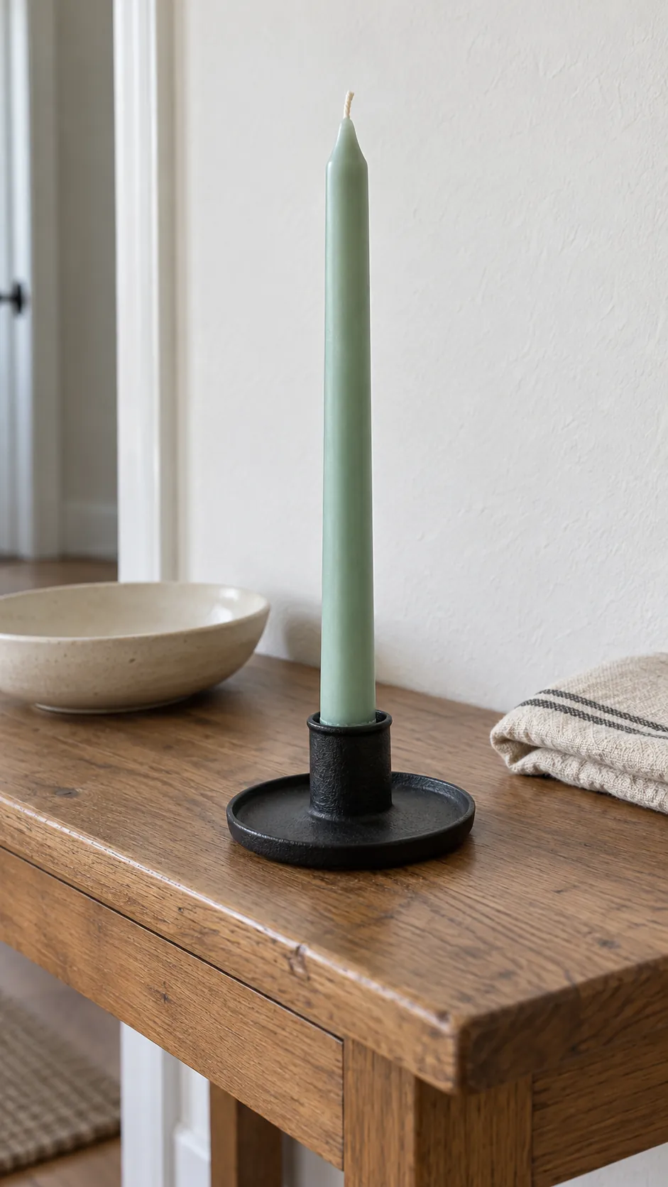 Unlit mint taper in a dark holder on an oak console