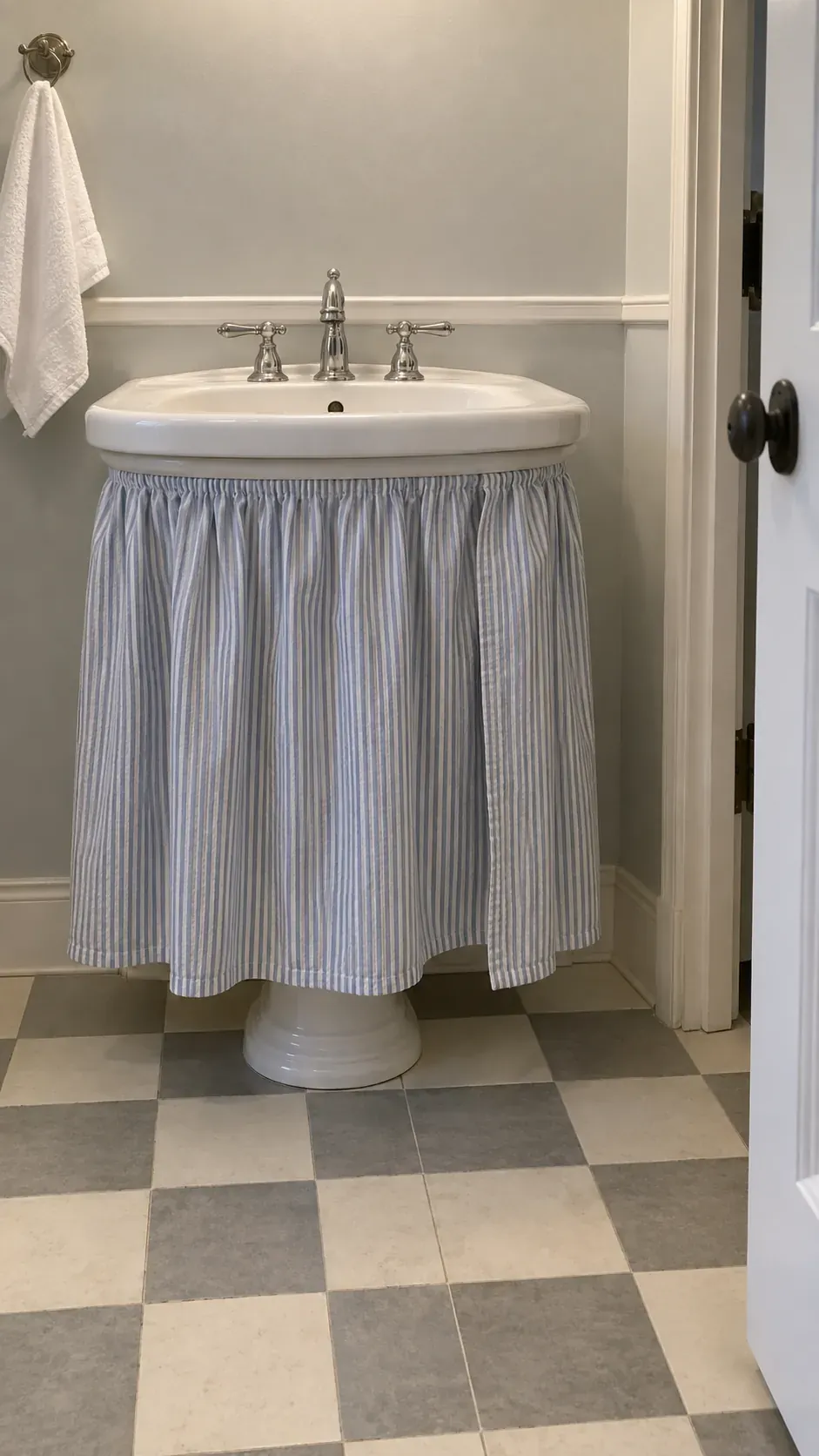 Removable striped sink skirt, low frontal view, checkerboard floor and neutral evening light