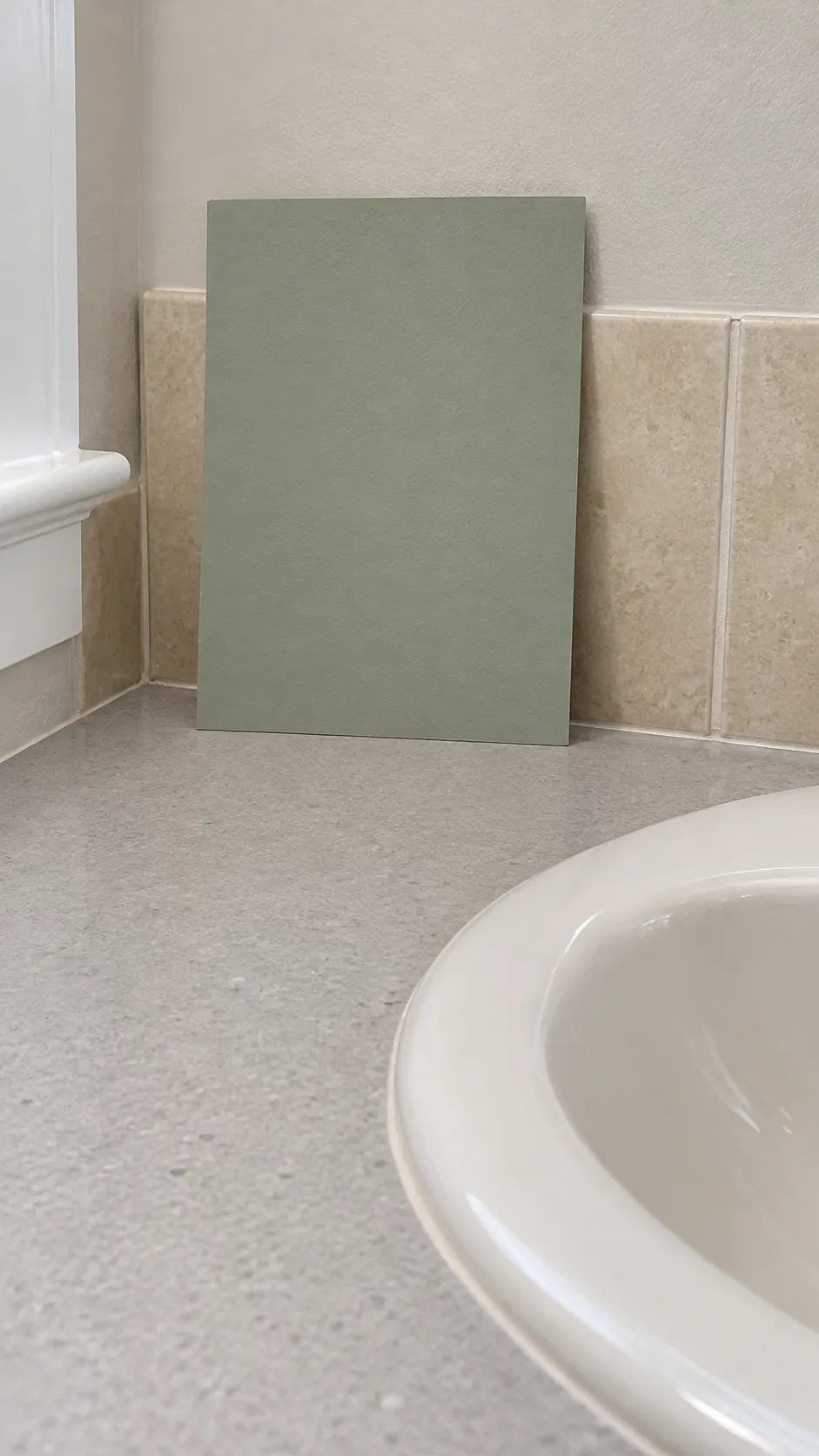 Paint sample checked beside ceramic and beige tile in an existing powder room