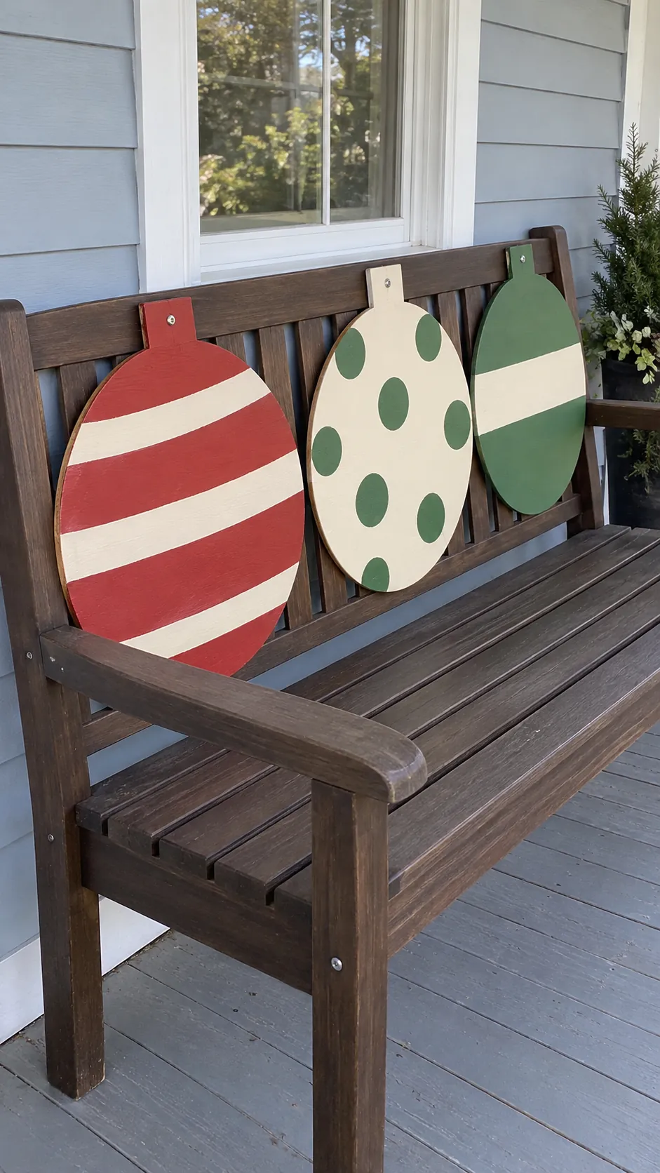 Painted wooden baubles on a porch bench as a DIY outdoor Christmas decoration