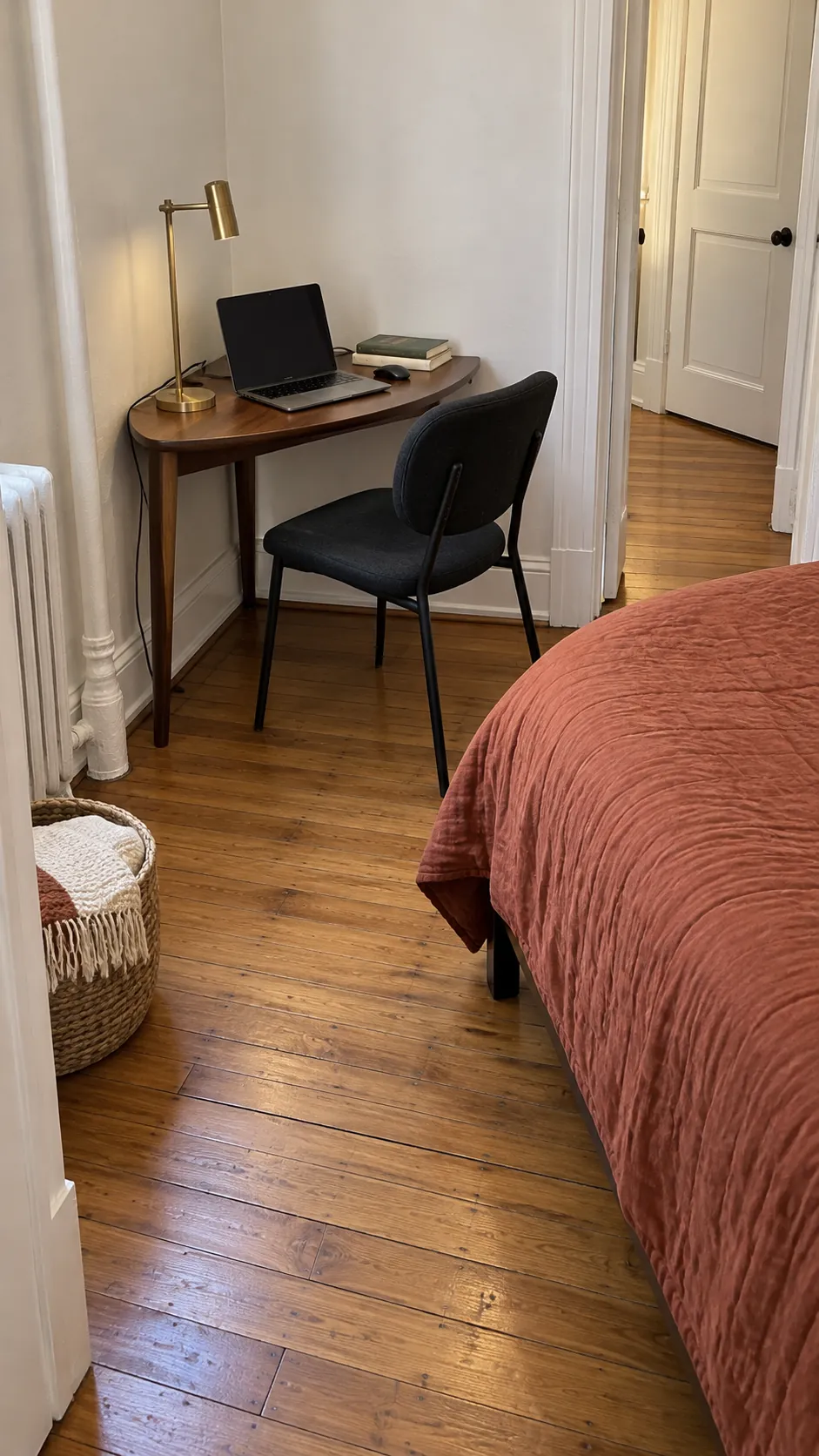 Compact corner desk near the foot of a bed