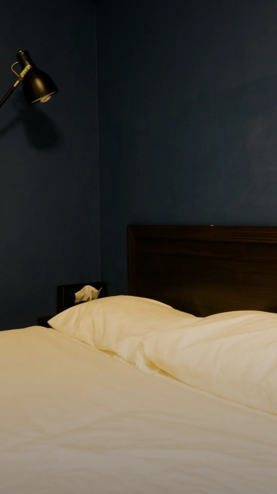 Warm amber LED strip glowing behind a wooden headboard creating ambient bedroom light for bedtime reading